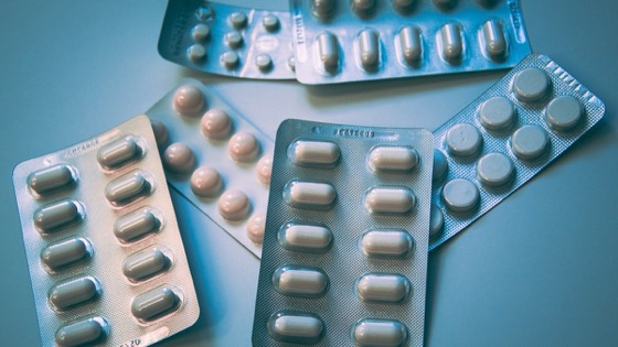 नीली सतह पर सफ़ेद और गुलाबी tablets के कई बिना brand वाले blister packs